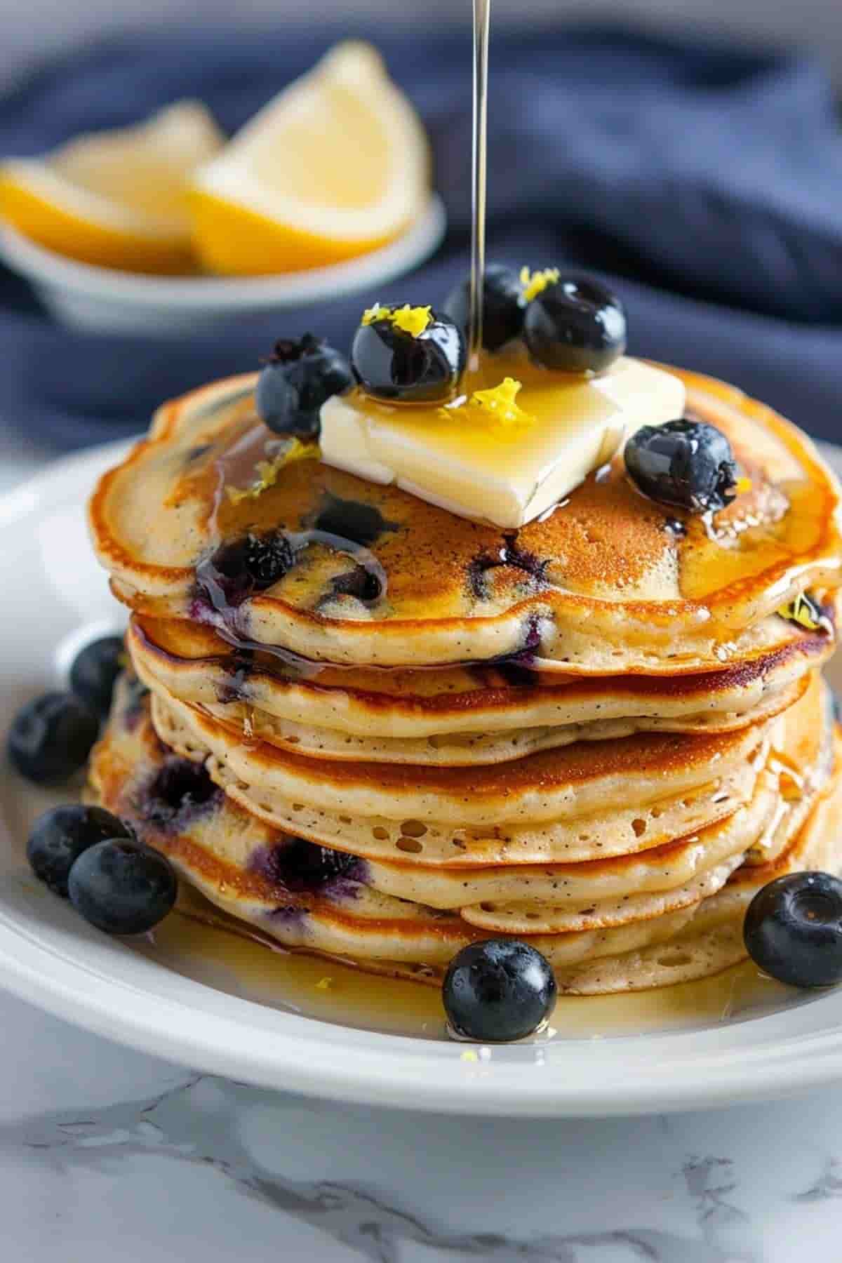 Blueberry lemon pancakes stacked with syrup and lemon
