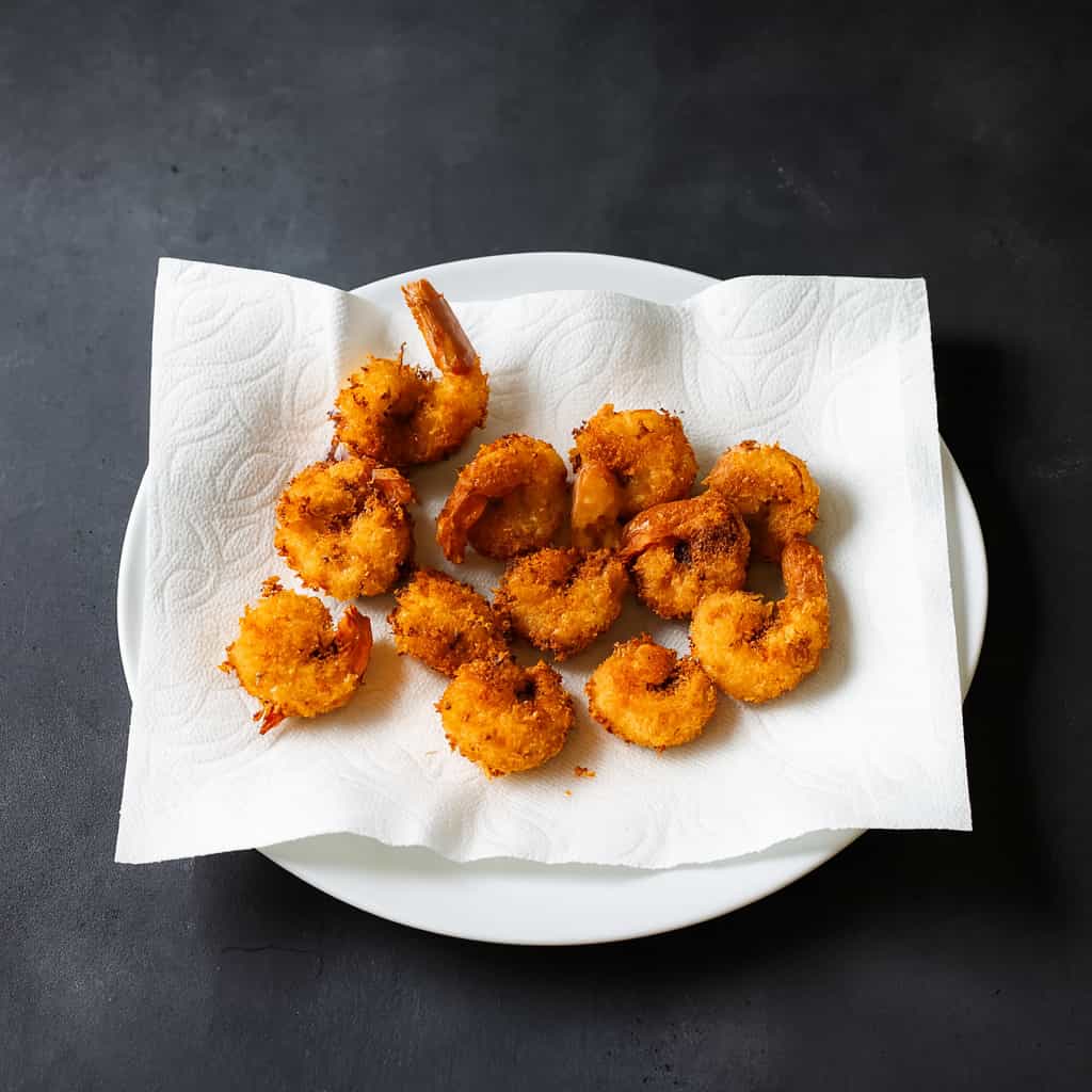 Shrimp coated in panko and coconut, Frying shrimp in hot oil, Freshly fried coconut shrimp