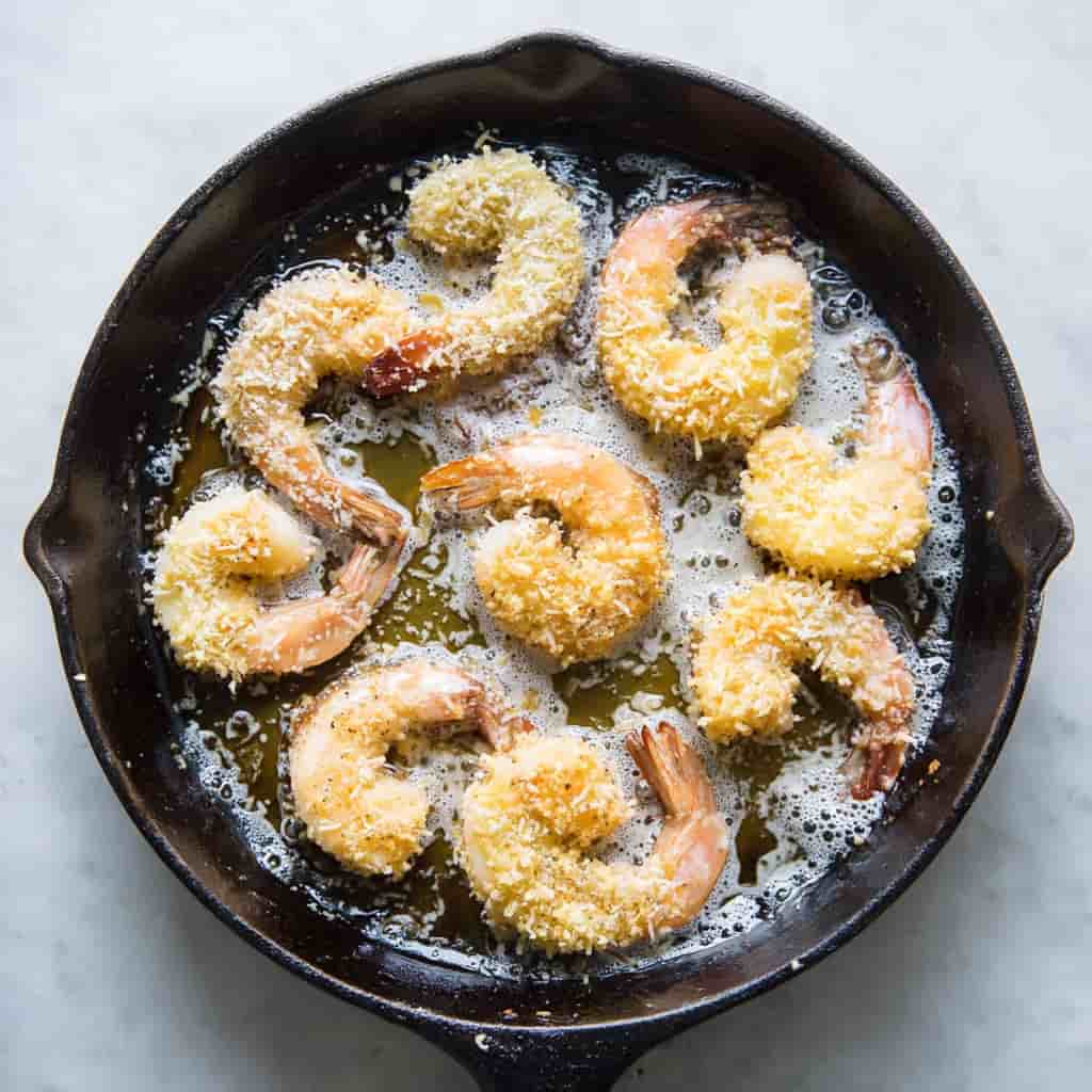 Shrimp coated in panko and coconut, Frying shrimp in hot oil, Freshly fried coconut shrimp